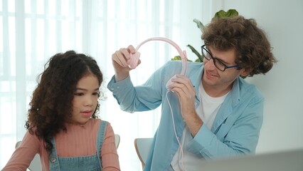 Caucasian dad put headphones on daughter while girl learning code. Father take care schoolgirl...