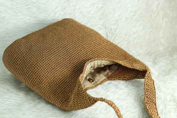 Crocheted handmade milky brown bag on furry white blanket.