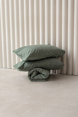 Two pillows in green pillow cases and blanket. Bed linen set. Fabric boiled cotton