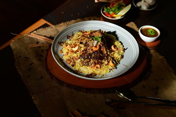 Mutton Mandi Rice. A delicious plate of Indonesian Nasi Goreng, a savory fried rice dish, served with a side of chili sauce and fresh vegetables.