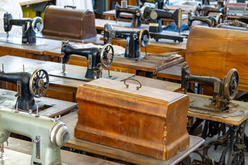 row of vintage sewing machines with wooden covers arranged in a tailoring workshop