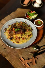 Mutton Mandi Rice. A delicious and hearty plate of biryani, a flavorful rice dish, served with a small bowl of curry and garnished with fresh herbs.