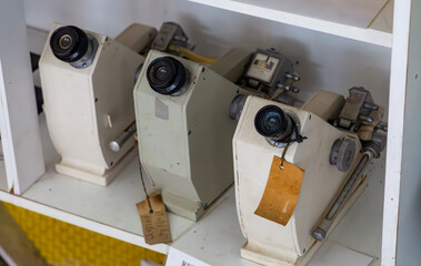 Old projection microscopes on a shelf. Optical devices with lenses used for displaying magnified...