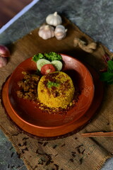 A delicious plate of Chicken Khichuri With Green Salad, garnished with fresh vegetables, presented on a rustic clay plate.