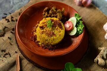 A delicious plate of Chicken Khichuri With Green Salad, garnished with fresh vegetables, presented on a rustic clay plate.