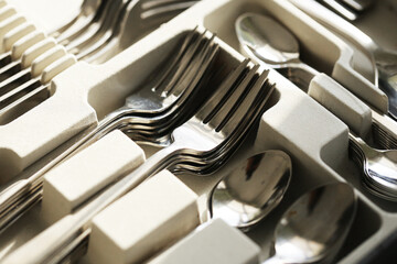 Shiny cutlery set in box. Forks spoons and knives neatly arranged. Stainless steel utensils in...