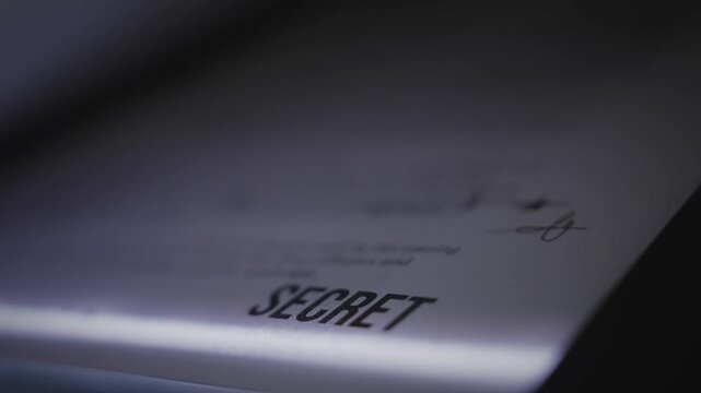 Extreme close up on report document labelled Top Secret being scanned or copied. Paper on scanner or photocopy machine tray. Sensitive government classified information is stolen or exposed by spy