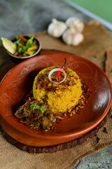 A beautifully presented Beef Khichuri With Green Salad dish with a side of salad and a lemon wedge, served on a rustic wooden surface.
