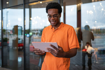 Smiling man using a tablet outside a modern building