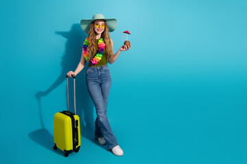 Young woman in casual outfit with travel bag and drink posing against bright blue background
