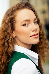 Confident young woman with a professional look outdoors in an urban setting, styled in a green...