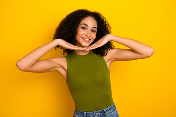 Confident young woman posing on vibrant yellow background in casual fashion style with a green top...