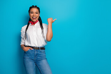 Confident young woman posing with a bright smile and vibrant fashion against a bright blue backdrop