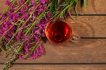 Medicinal herbal tea or fireweed infusion in a glass with flowers, alternative folk medicine concept, green pharmacy advertisement, collection of useful herbs for treatment according