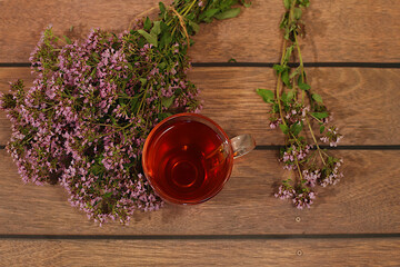 Oregano infusion in a glass with a bouquet of flowers, Medicinal herbal tea, the concept of alternative folk medicine, advertising a green pharmacy, a collection of useful herbs for treatment
