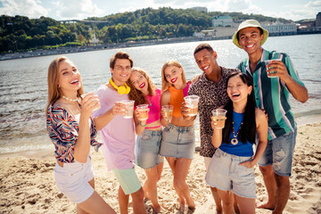 Buddies celebrating summer outdoors near a river, enjoying drinks, making memories, and sharing...