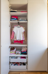 Organized wardrobe with children's clothes. Closet with clothes.