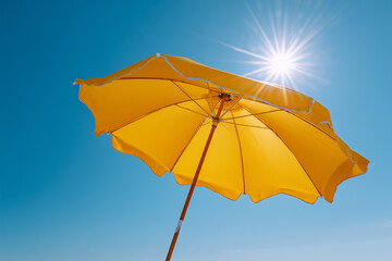 Yellow beach umbrella under bright summer sun, vibrant sunny day at the beach