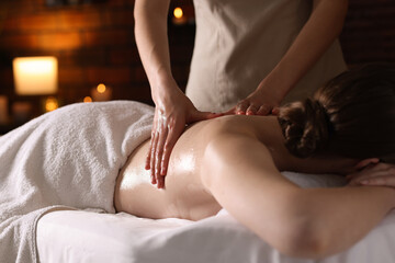 Woman receiving back massage with oil in spa salon, closeup