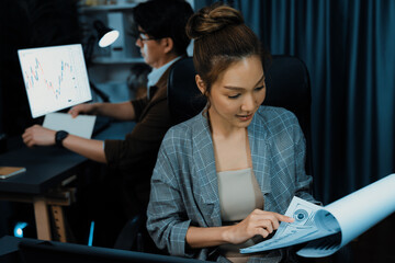 Businesswoman with stressful face looking document paperwork file while coworker trading stock...