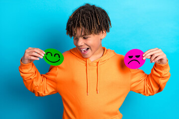 Boy Holding Happy and Sad Faces on Colorful Background, Expressing Emotions and Playfulness