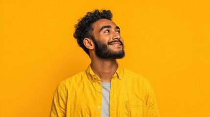 Happy joyful smiling young indian man looking aside up thinking of new good opportunities, dreaming, feeling inspired and proud standing isolated on yellow background. Portrait, no logos, no brands