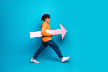 Young boy holding a pink arrow against blue background, highlighting casual style and vibrant...