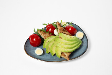 Toasts with avocado, tomatoes, arugula, and boiled eggs on a plate, isolated on white background