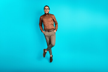 Young professional man in formal attire smiling confidently against a vibrant teal background,...