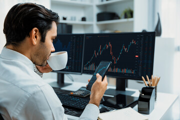 Trader businessman holding coffee cup focusing on dynamic on phone, stock exchange investment...