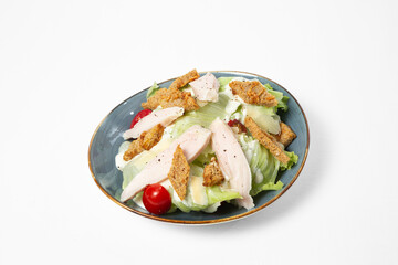 Salad with chicken, iceberg lettuce, cherry tomatoes, wheat croutons, and creamy dressing on a plate, isolated on white background