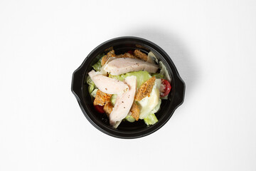 Salad with chicken, iceberg lettuce, cherry tomatoes, wheat croutons, and creamy dressing on a plate, isolated on white background