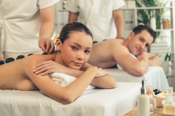 Hot stone massage at spa salon in luxury resort with day light serenity ambient, blissful couple...