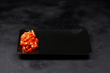 Fresh cherry tomatoes arranged on a sleek black plate, showcasing vibrant colors against a dark textured background, perfect for culinary presentations and food styling