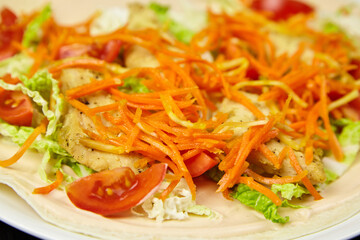 Freshly prepared tortilla wrap filled with grilled chicken, shredded carrots, lettuce, and cherry tomatoes, showcasing vibrant colors and healthy ingredients in a delicious meal presentation