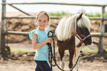 Cute little girl petting a pony in a farm