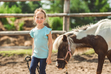 Cute little girl petting a pony in a farm