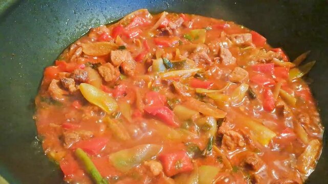 vegetable stew being cooked on the stove in a pot with tomatoes, bell peppers