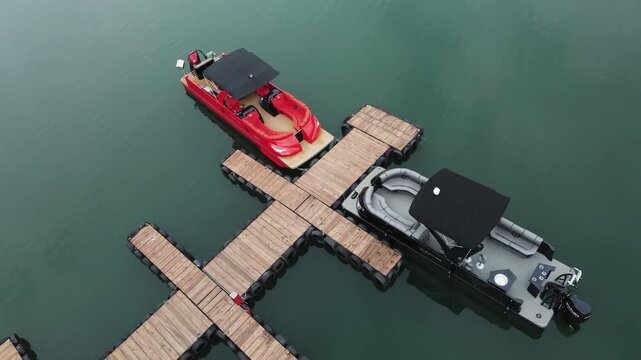 Drone shot two sleek pontoon boats docked at a wooden pier on Guatape Reservoir in Antioquia