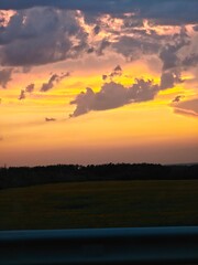 Beautiful sunset over a grassy field surrounded by trees in the late evening sky