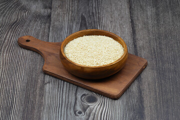 Top view closeup of freshly harvested white sesame in wooden bowl isolated on wooden background...