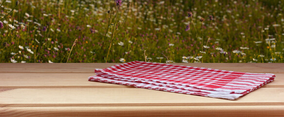 Checkered napkin lying on wooden table with meadow background