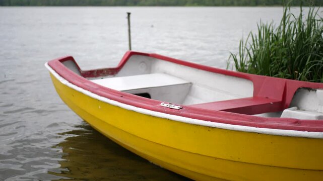 A yellow rowboat slowly sways on small lake waves near the shore. Peaceful outdoor scene with gentle motion on the water during a calm day.

