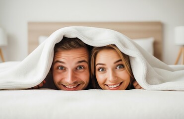A joyful married couple hides under blanket, staring playfully into camera, eyes filled with warmth and intimacy