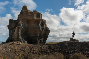 Man standing on a ridge overlooking a massive, layered rock monolith. Nature concept.
