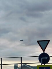Airplane approaches landing at dusk over residential area near traffic sign