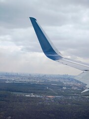Aerial view of urban landscape with airplane wing in the foreground during cloudy weather
