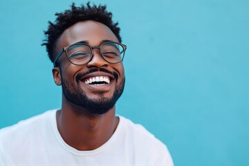 Obraz premium Joyful Man Smiling Against a Bright Blue Background During a Sunny Day Outdoors