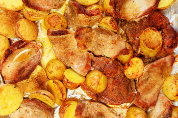 Closeup of roasted pork meat and potatoes baked in oven unhealthy food