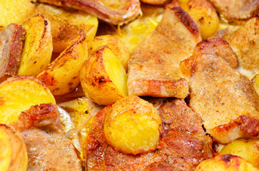 Unhealthy oven baked pork meat with roasted potatoes junk greasy food